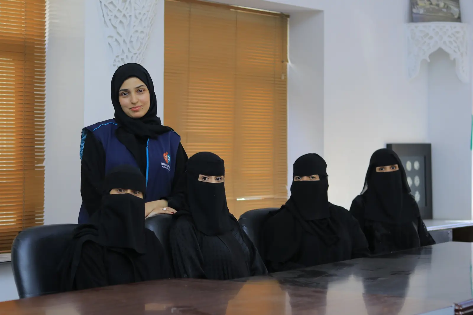 Five women from the Nahbal team in a meeting space, one wearing a Nahbal vest