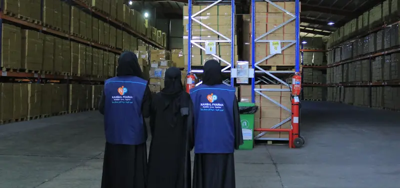 Three Nahbal Pharma team members in branded workwear inside an organised warehouse storage area